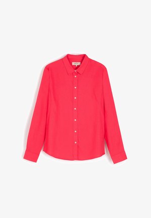 Długotrwała koszula z długim rękawem w jasnoróżowym kolorze, wykonana z lekkiego materiału. Posiada zapięcie na guziki z przodu, klasyczny kołnierzyk oraz zaokrąglony dół.