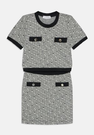 Compleu din două piese cu un top cu mânecă scurtă și fustă, având un model de text alb-negru, cu detalii negre și buzunare decorative în față.