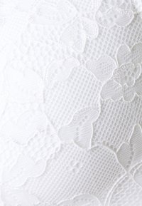 Witte kant stof met bloemmotieven en een gestructureerd roosterontwerp, met zachte randen en ingewikkelde details overal.