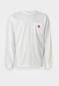 White long-sleeve T-shirt made of cotton, featuring a left chest pocket with a red heart patch. Classic crew neck and ribbed cuffs.