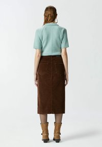 Menta zeleni kratki rukav svijetlopričajući pulover s rebrastom teksturom, uparen s smešnim midi suknjom od kordura i svijetlosmeškim čizmama do gležnjeva s kopčama.