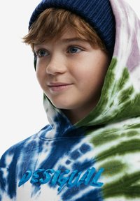 Mikina s kapucňou so vzorom tie-dye v modrej, zelenej a bielej farbe; logo "DESIGUAL" vo vyvýšenej tyrkysovej farbe; mäkká textúra.