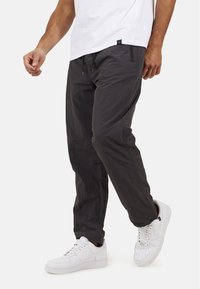 Ciemnoszare, lekkie spodnie z elastycznym pasem i regulowanym sznurkiem. Posiadają boczne kieszenie oraz dopasowany krój nogawek.