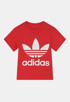 T-shirt rouge à manches courtes avec un grand logo Adidas trefoil blanc et le mot "adidas" imprimé en dessous à l'avant.
