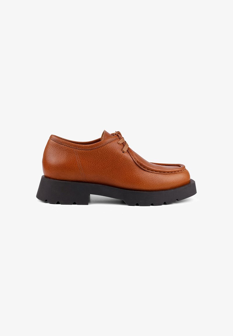 Brown leather shoe with a textured finish, lace-up design, and a thick black rubber sole. Features a rounded toe and stitched accents.