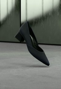 Modré lodičky s špičatou špičkou, matnou textúrou a nízkym hranatým podpätkom, navrhnuté pre pohodlie a stabilitu. Hladká vnútorná podšívka.