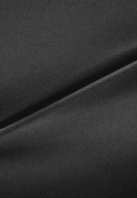 Tela negra con una textura suave y mate, que presenta sutiles resaltos y una apariencia sin costuras, doblada con líneas limpias.