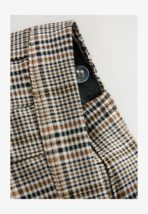 Kelnės, dėvimos ruda, juoda ir balta šachmatų raštu. Su mygtukų užsegimu ir kišenių detalėmis. Struktūrizuota tekstūra.