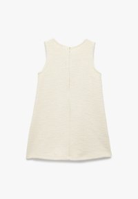 Vestido sin mangas de color crema, hecho de tejido texturizado, con un cierre en la parte central de la espalda y un dobladillo ligeramente curvado para un ajuste relajado.