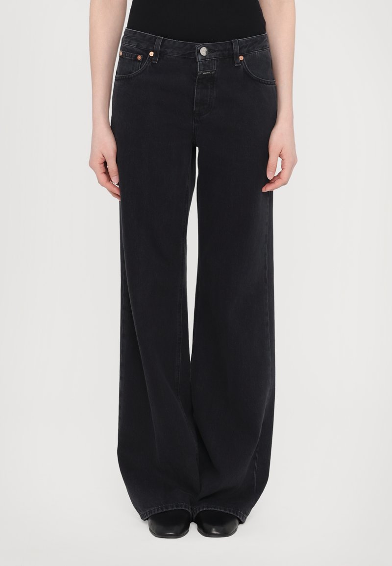 Vide ben svarte denimjeans med høy midje, fem lommer og kontrasterende kobbermetall-detaljer. Glatt tekstur, minimale detaljer.