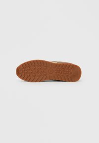 Smeđa gumena vanjska potplata s uzorkom gaznoga sloja, s logotipom i teksturiranim detaljima za poboljšano prianjanje.