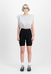 Sivý krátky sveter s okrúhlym výstrihom a elastickým lemom, skombinovaný s čiernymi bicyklovými šortkami. Model má na sebe biele ponožky a čierne tenisky.