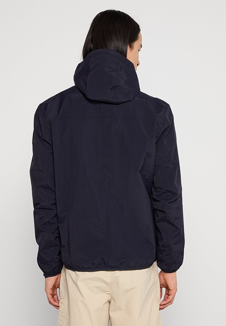 Giacca con cappuccio blu navy realizzata in un tessuto leggero, con chiusura con zip, polsini elastici e una superficie liscia.