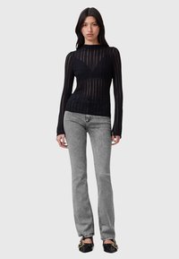 Musta pitkähihaisen yläosa, jossa pystysuoria läpikuultavia raitoja, yhdistetty harmaisiin liehuviin farkkuihin. Yläosassa on pyöreä pääntie ja istuva malli.