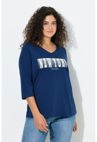 Granatowy top z dekoltem w serek i rękawami do połowy przedramienia, z białym napisem "NEW YORK" oraz "miasto marzeń" w wyrazistym graficznym wzorze.