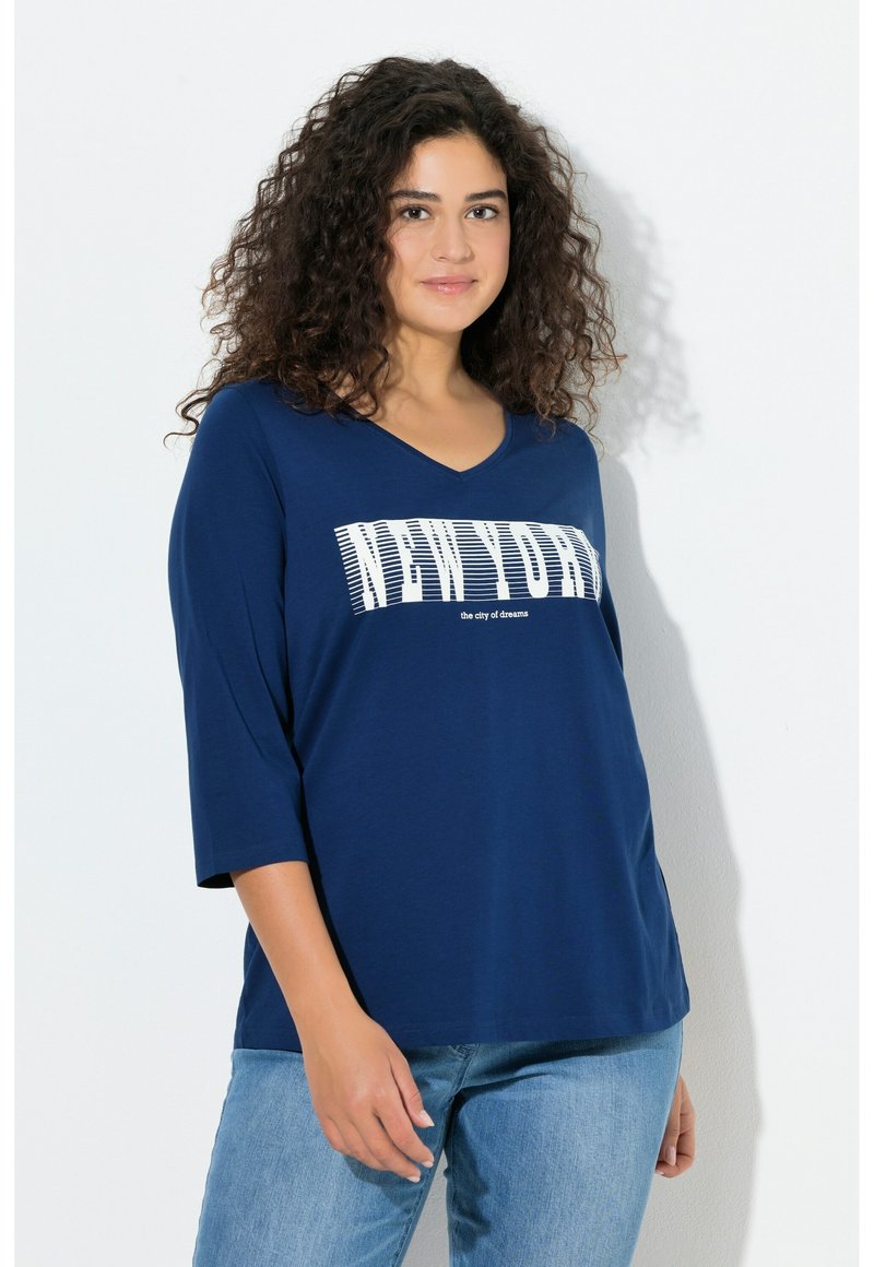 Granatowy top z dekoltem w serek i rękawami do połowy przedramienia, z białym napisem "NEW YORK" oraz "miasto marzeń" w wyrazistym graficznym wzorze.