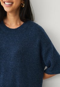 Marineblå strikket sweater med rund halsudskæring og korte ærmer, der har en blød, struktureret finish og en afslappet pasform.