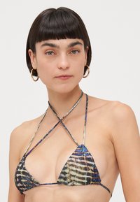 Trikoten bikini zgornji del v večbarvnem živalskem vzorcu, z tankimi naramnicami in nabranim središčem. Material se zdi mehak z rahlim sijajem.