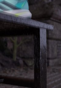 Scarpa da ginnastica turchese e bianca appoggiata sul bordo di un tavolo di legno nero con sfondo esterno sfocato.