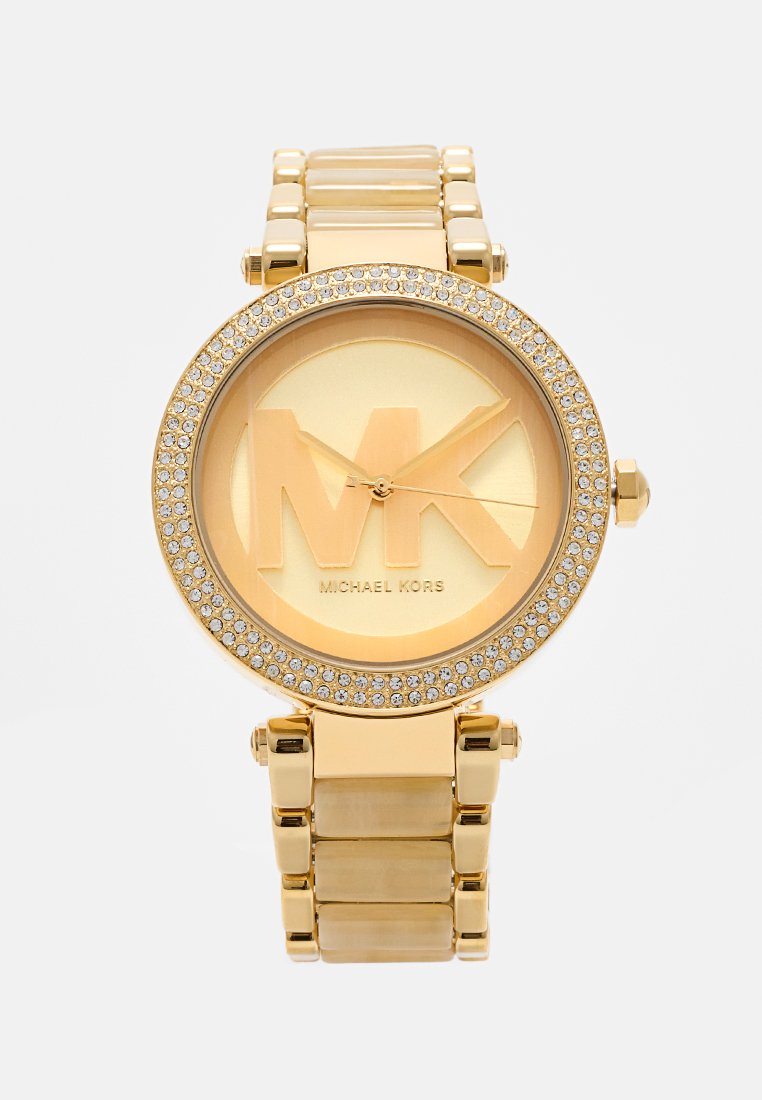 Montre dorée avec un cadran rond, arborant un logo "MK" en relief et une lunette ornée de cristaux. Design de bracelet à maillons en métal avec une finition brillante.