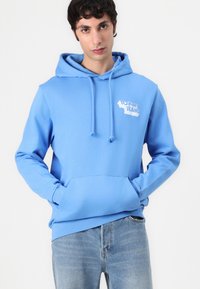 Lichtblauwe hoodie met een voorvak en het witte "Tommy Jeans" logo. Gemaakt van katoen, met een zachte textuur en een relaxte pasvorm.