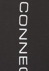 T-shirt en coton noir avec un texte vertical blanc qui dit "CONNECT" dans une police sans serif moderne. Texture lisse, sans motifs supplémentaires.