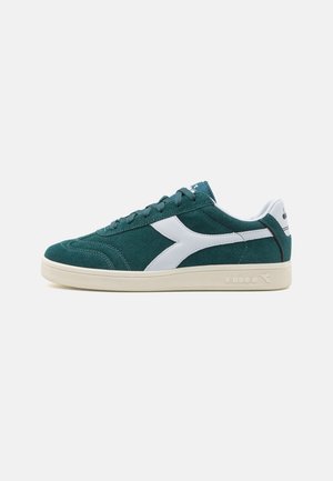 Sneakers in camoscio verde con dettagli bianchi, caratterizzati da un design classico low-top, superficie texturizzata e una suola in gomma con dettagli di branding.