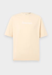 Μπεζ βαμβακερό κοντομάνικο T-shirt με λευκό κείμενο "Selected" στο κέντρο του στήθους, σε απλό φόντο.