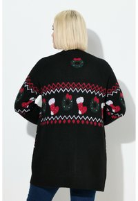 Schwarze Strickjacke mit festlichem Design, das rote und weiße Strümpfe und grüne Kränze zeigt, mit Zickzackmuster und weicher Textur.