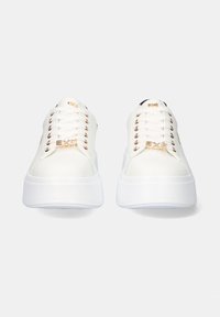Zapatillas blancas con un acabado de cuero suave, que presentan ojales dorados y una suela blanca elevada. Acabadas con un talón negro y detalles de marca.