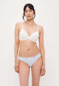 Witte beha met een gladde textuur en dunne bandjes, gecombineerd met blauwe onderbroek met bloemenprint en gekrulde randjes met een delicate afwerking.