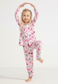 Rosa Baumwollschlafanzüge mit Blumen- und Bandmustern, bestehend aus einem knöpfbaren Oberteil und passenden Hosen. Das Kind posiert spielerisch, barfuß.