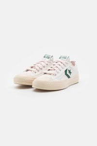 Zapatillas de lona en blanco con detalles en verde, puntera redonda, diseño con cordones, suela de goma texturizada, con un logo de estrella en el lateral.