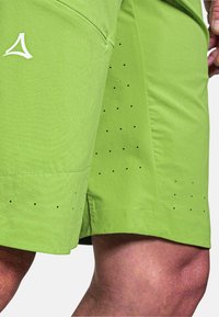 Limenvihreät urheilushortsit, jotka on valmistettu kevyestä kankaasta. Sisältää läpivientejä hengittävyyden lisäämiseksi ja valkoisen logon sivulla.