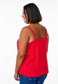 Czerwona bezrękawnik z regulowanymi ramiączkami, charakteryzujący się miękką teksturą i luźnym krojem, w połączeniu z dżinsowymi spodniami w truskawkowe motywy.