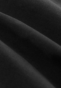 Tessuto nero con una texture liscia, caratterizzato da un sottile motivo a coste e pieghe drappeggiate, che mostra una leggera lucentezza alla luce.