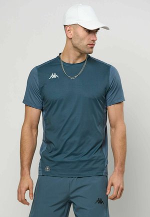 Tummanvihreä urheilupaita, jossa on lyhyet hihat, valmistettu sileästä ja kevyestä kankaasta. Rinnan kohdalla valkoinen logo ja hienovarainen tekstuuri.