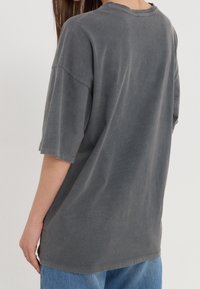Przesadzony szary bawełniany t-shirt z krótkim rękawem, okrągłym dekoltem i miękkim, teksturowanym wykończeniem. Subtelne szwy i luźny krój.