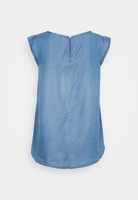 Denimipaita lyhyillä liehuhihnoilla, takana napitus ja kaarrettu helmanta. Vaaleansininen väri, joka on sileä ja pehmeä.