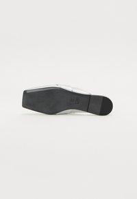 Sølv hælhæl sandal med en teksturert overdel og glatt svart gummisåle, med bred stroppdesign for sikker passform.