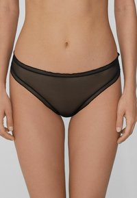 Culotte de bikini en maille noire à texture lisse, dotée d'une large ceinture et de bords festonnés, conçue pour une coupe élégante.