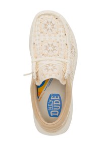 Lichtbeige gehaakte sneaker met een zachte stoffen bovenkant, crèmekleurige accenten en een witte zool. Complex patroon zichtbaar op het stoffen oppervlak.