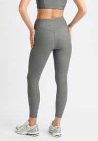 Högmidjade grå ribbade leggings med en sömlös midjeband och texturerad tyg, kombinerat med vita och grå sportskor.