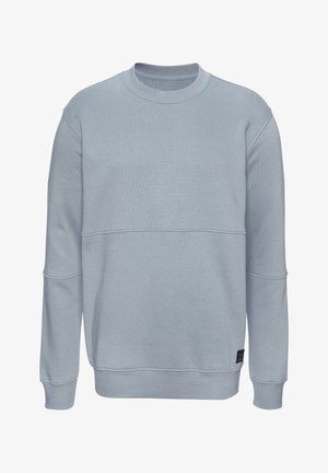 Light blue crewneck sweatshirt with long sleeves, subtle seam detailing across the chest and arms, and a small black tag near the hem.