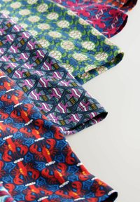 Vier gemusterte Stoffmuster: rote Hummer, Schildkröten in Grüntönen, Oktopus und geometrische Designs in Blau-, Pink- und Grüntönen.