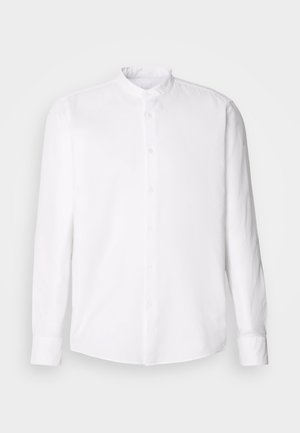 Valge pika varrukaga särk, millel on püstkraed, nööpidega eesmine lend, tekstureeritud kangas ja klassikaline lõige. Muster või aksessuaarid puuduvad.