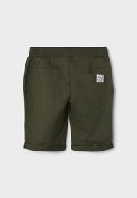 Green cotton shorts with a rolled hem, elastic waistband, and a rear patch pocket featuring a label. Smooth texture and simple design.