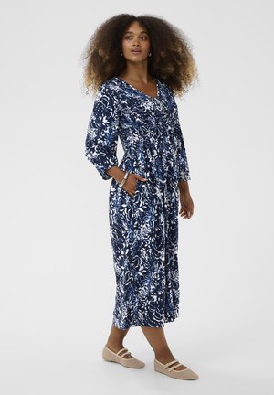Marineblauwe jurk met bloemenprint, lange mouwen, V-hals en zakken; gemaakt van zachte stof en met een vloeiende, enkelhoge lengte.