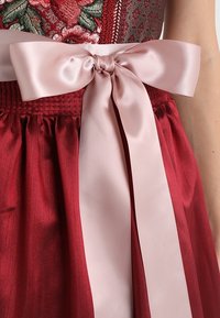 Robe en satin rouge avec une jupe froncée, un nœud en satin rose à la taille, une broderie florale complexe sur le corsage et des détails texturés.