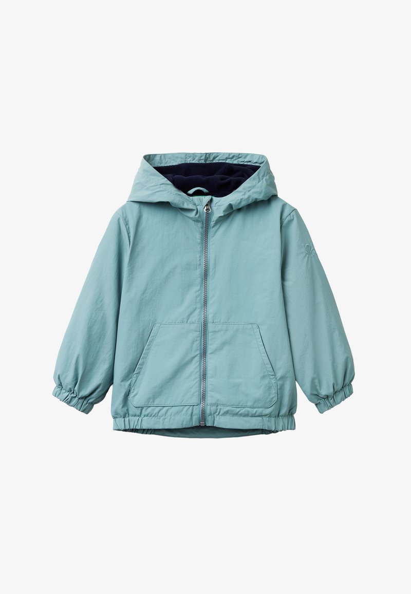 Světle modrá bunda s kapucí a předním zipem, elastickými manžetami, dvěma předními kapsami a tmavě modrou podšívkou. Měkká, voděodolná tkanina.